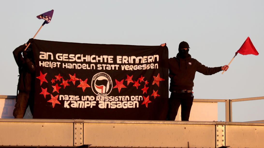 Die Aufnahme vom 8. Mai 2018 aus Demmin (M-V) zeigt "Antifa"-Demonstranten, die mit einem Transparent ("An Geschichte erinnern heißt handeln statt vergessen - Nazis und Rassisten den Kampf ansagen") gegen einen Aufmarsch der NPD demonstrieren. (Quelle: picture alliance / Bernd Wüstneck/dpa | Bernd Wüstneck) Die Aufnahme vom 8. Mai 2018 aus Demmin (M-V) zeigt "Antifa"-Demonstranten, die mit einem Transparent ("An Geschichte erinnern heißt handeln statt vergessen - Nazis und Rassisten den Kampf ansagen") gegen einen Aufmarsch der NPD demonstrieren.