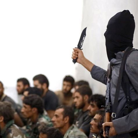 Die undatierte Aufnahme, die am 27. August 2014 im Internet veröffentlicht wurde, zeigt einen IS-Kämpfer mit einem Messer und einer automatischen Waffe neben gefangenen syrischen Soldaten in Raqqa (Syrien). (Quelle: AP Photo/picture alliance) Die undatierte Aufnahme, die am 27. August 2014 im Internet veröffentlicht wurde, zeigt einen IS-Kämpfer mit einem Messer und einer automatischen Waffe neben gefangenen syrischen Soldaten in Raqqa (Syrien).