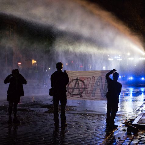 Aktivisten halten bei Nacht in Hamburg ein Transparent, auf dem ein anarchistisches Symbol zu sehen ist. (Quelle: Chantal Pinzi / EyeEm / Getty Images) Aktivisten halten bei Nacht in Hamburg ein Transparent, auf dem ein anarchistisches Symbol zu sehen ist.