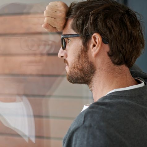 Die Aufnahme zeigt einen nachdenklichen jungen Unternehmer, der sich an eine Fensterschreibe in seinem Büro lehnt (Quelle: jeffbergen / E+ / Getty Images) Die Aufnahme zeigt einen nachdenklichen jungen Unternehmer, der sich an eine Fensterschreibe in seinem Büro lehnt