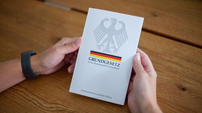 The shot shows the hands of a man holding the Basic Law for the Federal Republic of Germany (Source: K. Schmitt/Fotostand/picture alliance) The shot shows the hands of a man holding the Basic Law for the Federal Republic of Germany