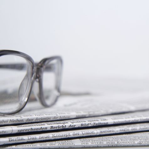 The shot shows a stack of newspapers against a white background on which a pair of glasses is lying. (Source: Westend61/picture alliance) The shot shows a stack of newspapers against a white background on which a pair of glasses is lying.