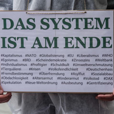 The photo taken on May 1, 2020 in Munich shows a man holding a sign reading "The system is finished" as part of a demonstration. (Source: Sachelle Babbar/ZUMA Press/picture alliance) The photo taken on May 1, 2020 in Munich shows a man holding a sign reading "The system is finished" as part of a demonstration.